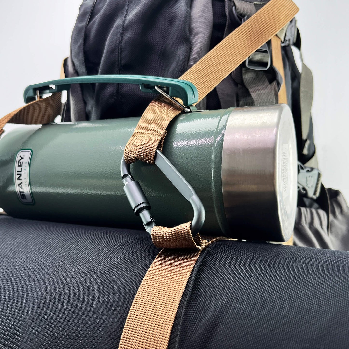 packpal straps securing a bottle and a pad to a backpack with the help of lock carabiners