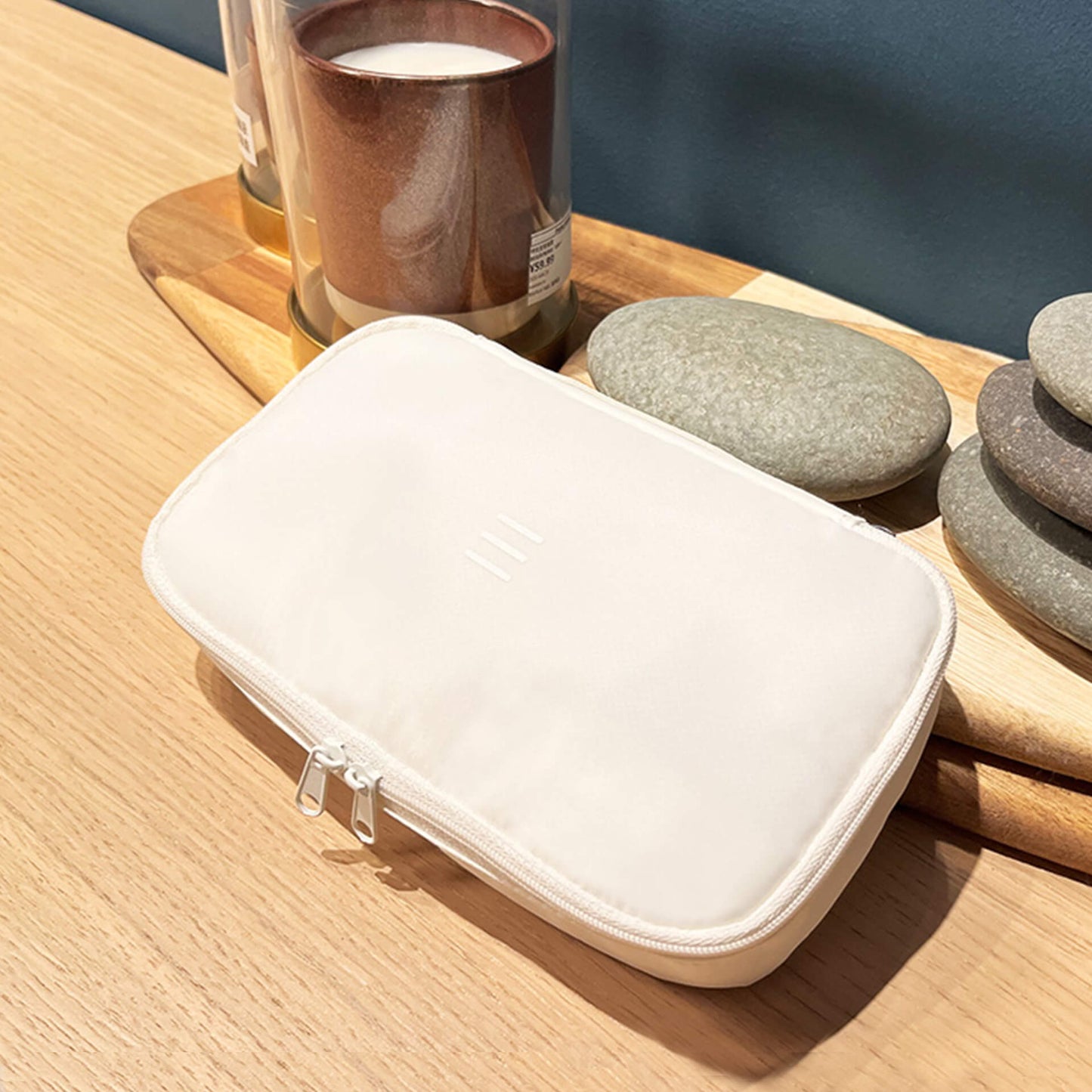 a white 190+ organizer pouch on a table with scented candles and aroma stones