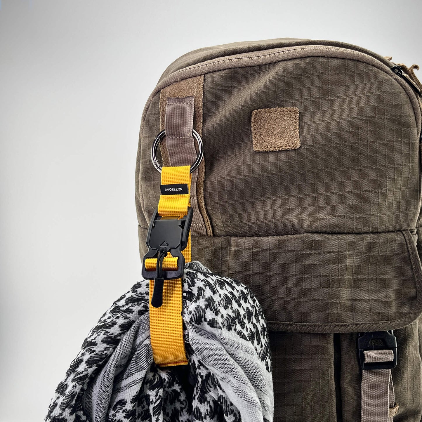 a yellow Snapal strap securing a gray scarf to a brown backpack