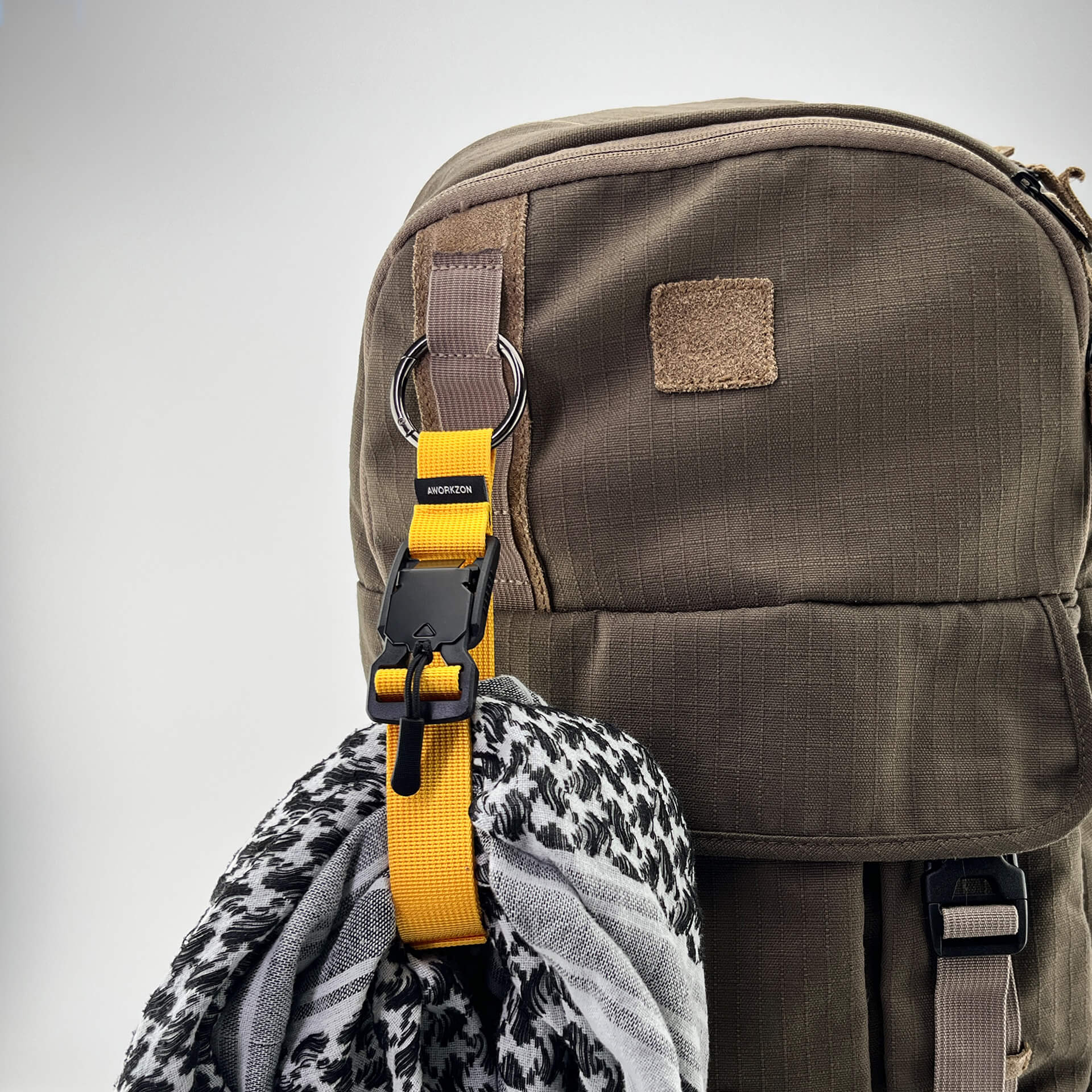 a yellow Snapal strap securing a gray scarf to a brown backpack
